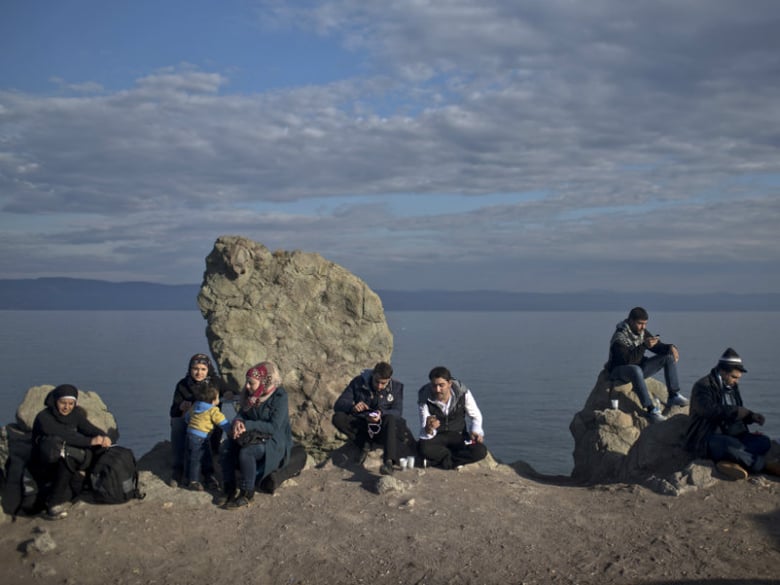 People relax after arriving by boat from neighboring Turkey on the northern shore of Lesbos, Greece, Tuesday, Nov. 10, 2015. Over half a million migrants and refugees have reached the Greek islands so far this year, a record number of arrivals.