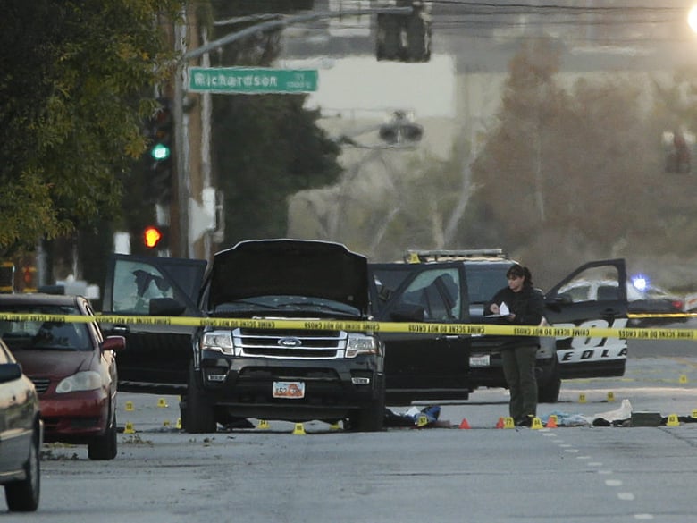 An investigator looks at a Black SUV that was involved in a police shootout with suspects, Thursday, Dec. 3, 2015, in San Bernardino, Calif.