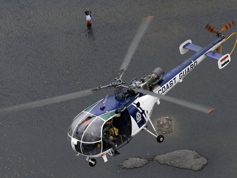 A flood-affected man waves to a coastguard chopper in Chennai, India, Saturday, Dec. 5, 2015.