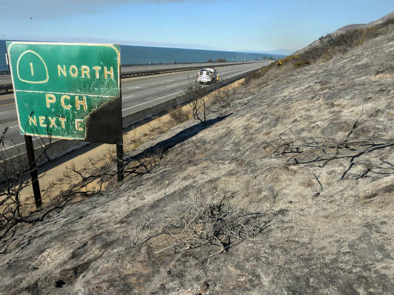 Parked on a closed US Highway 101, a Santa Barbara County Fire Department fire engine and crew douse a hot spot while working a Solimar wildfire in Ventura County, Calif. on Saturday, Dec. 26, 2015.