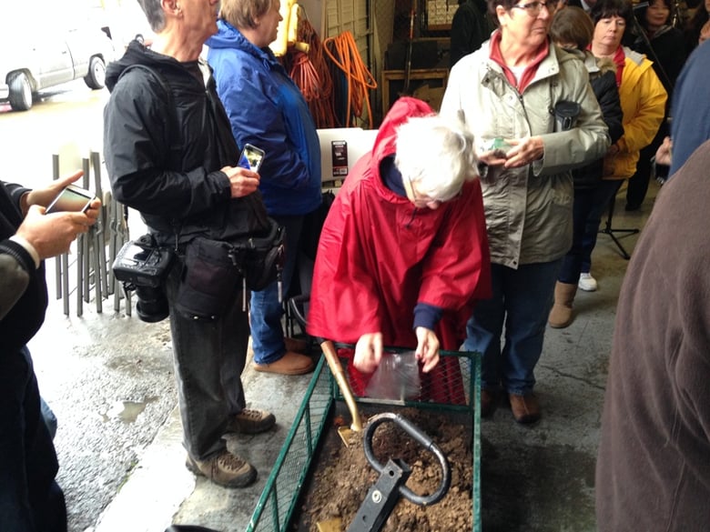 Patty Michel-Evleth empties a bag of dirt from her property into a wagon that was taken to the site of the new Friendship Park and scattered. Rains forced much of the ceremony indoors.