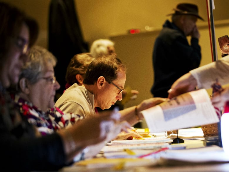 Election officials assist voters lining up to cast their ballots at a polling site for the New Hampshire primary Tuesday, Feb. 9, 2016, in Nashua, N.H. 
