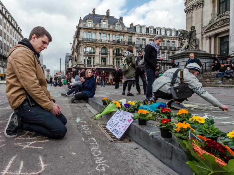 A man looks at flowers and messages outside the stock exchange in Brussels on Tuesday, March 22, 2016. Explosions, at least one likely caused by a suicide bomber, rocked the Brussels airport and subway system Tuesday, prompting a lockdown of the Belg