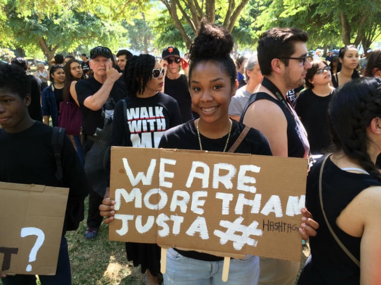Zamorian Sherman holds this sign at a Standing 4 Black Lives event. She says social media protests aren't enough to help solve the problem of violence against minorities.