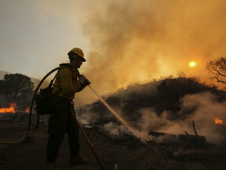 A firefighter battles a wildfire near Placerita Canyon Road in Santa Clarita, Calif., Sunday, July 24, 2016. Thousands of homes remained evacuated Sunday as two massive wildfires raged in tinder-dry California hills and canyons. 