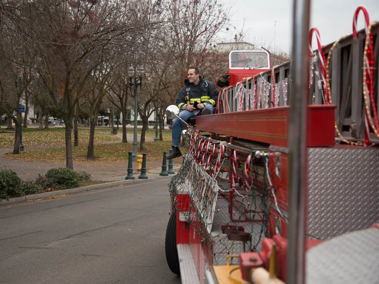 Probationary Firefighter Ben Guthrie rides to the Stockton Emergency Food Bank on board a 50s-era firetruck loaded with frozen turkeys on Thursday, Dec. 15, 2016. 
