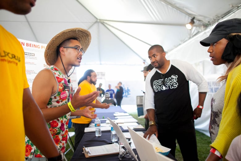 Matthew Vu, left, talks to local residents about issues that will be on the ballot during a music and art festival in Martin Luther King Jr. Park in South Los Angeles on Saturday, Sept. 3, 2016.