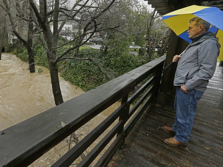 A man stands on a bridge as he watches the level of the San Anselmo Creek Tuesday, Feb. 7, 2017, in San Anselmo, Calif. 