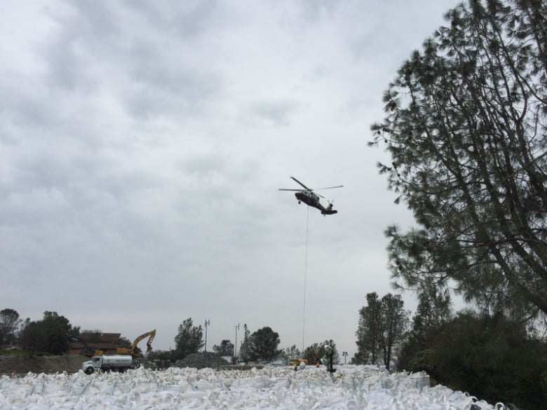 A helicopter prepares to lift a large bag of rocks to be used at the base of the Oroville Dam emergency spillway.