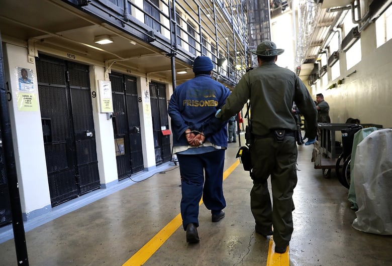 An armed corrections officer escorts a condemned inamte at San Quentin State Prison's death row. San Quentin houses the state's only death row for men.