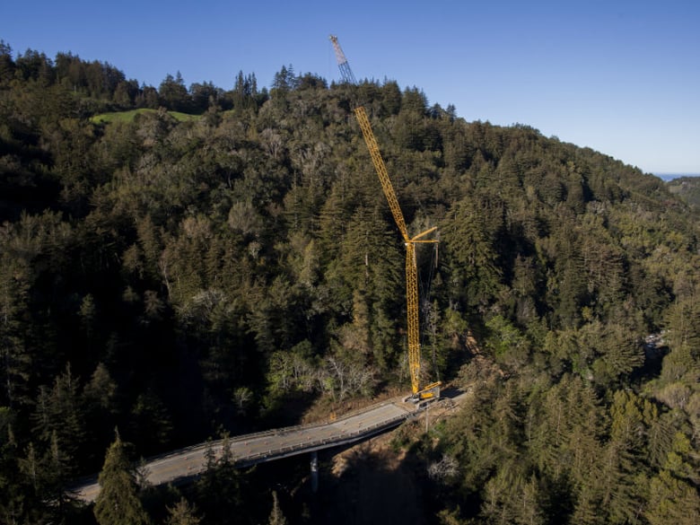 A crane sits on Highway 1 south of the Pfeiffer Canyon Bridge in Big Sur, Calif., Monday, March 13, 2017. The downed bridge along the California coast has split the Big Sur area in two.