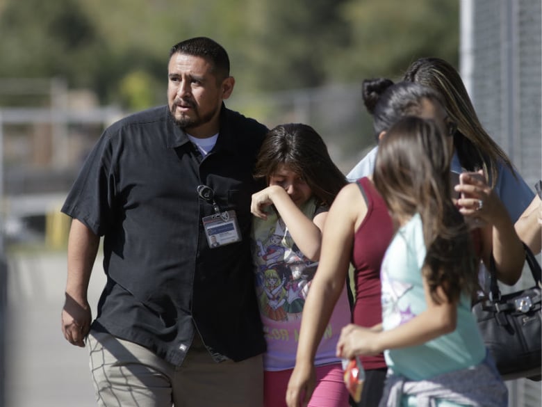 Camilo Rocha, left, comforts his daughter, Serina, a 11-year-old student at North Park Elementary School, after they were reunited at Cajon High School, Monday, April 10, 2017, in San Bernardino, Calif., after the deadly shooting on campus.