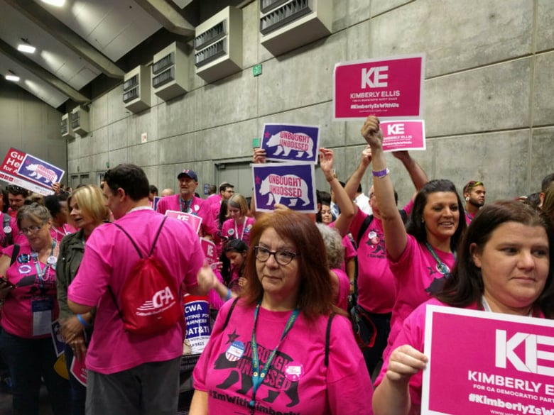 Supporters of Kimberly Ellis hold signs in the main convention chamber during the 2017 California Democratic Party Convention.