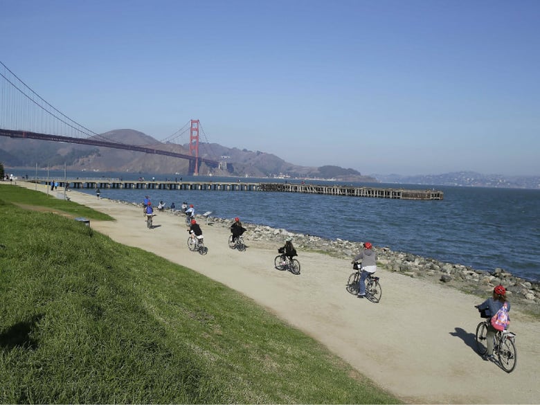 FILE - In this Nov. 25, 2014 file photo, a group of people on rental bicycles ride past Crissy Field toward the Golden Gate Bridge in San Francisco.