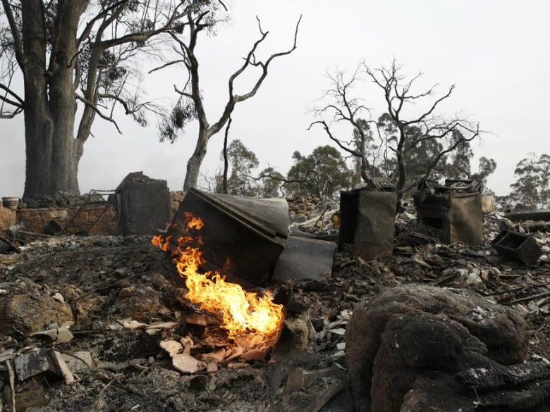Flames fed by a gas line, burns in the debris of a fire ravaged home, Tuesday, Oct. 10, 2017, in Napa, Calif.