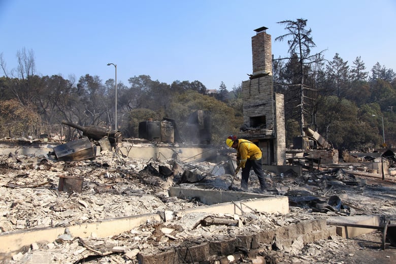 Berkeley firefighter Matt George picks through the ash of a Santa Rosa neighborhood looking for smoldering materials after deadly fires swept through the area in October 2017.