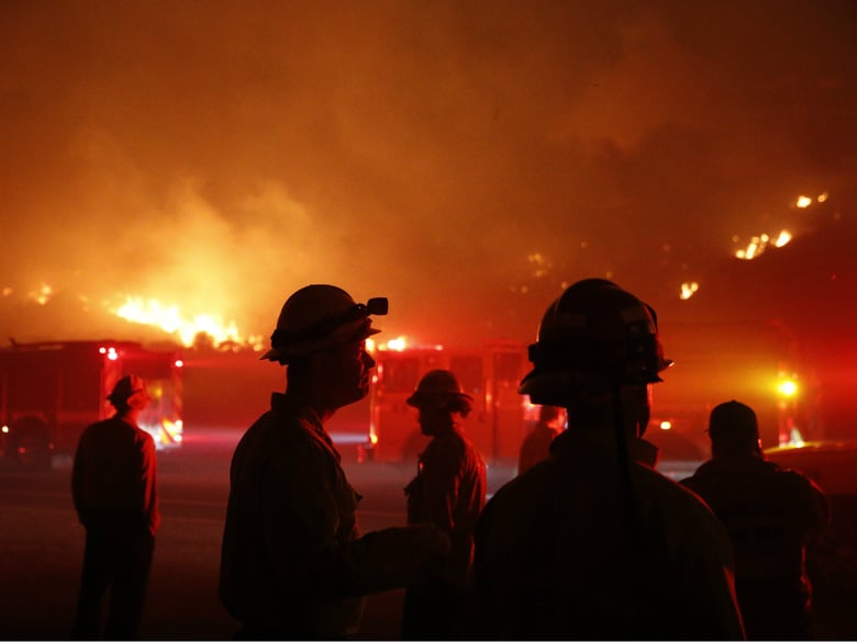 Firefighters gather in front of a residential area as a wildfire burns along the 101 Freeway Tuesday, Dec. 5, 2017, in Ventura, Calif. 
