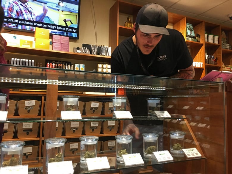 Torrey Holistics employee Taron McElroy arranges jars of cannabis in San Diego, Calif., Thursday, Dec. 14, 2017.