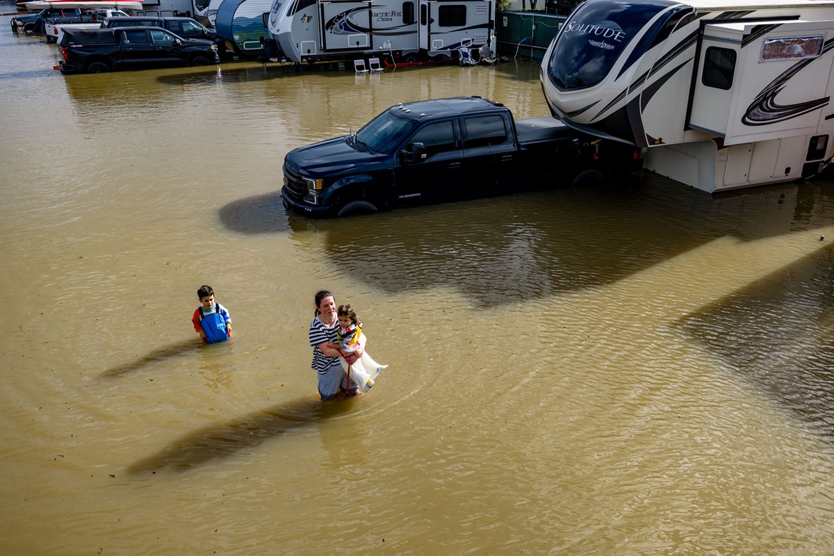 People wade through a recreational vehicle park flooded by a king tide on Jan. 3, 2026, near Corte Madera in Marin County, Calif.