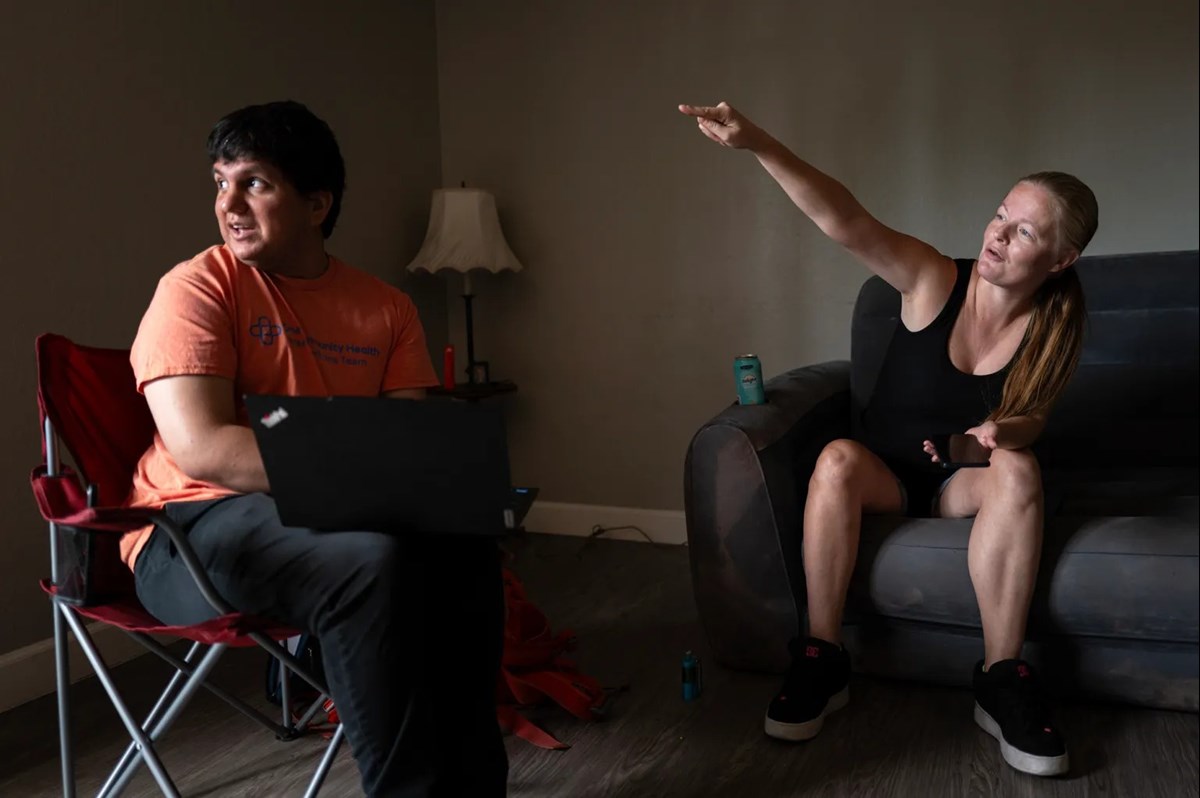 Jessica Scott, 35, gestures to where she used to live when she was pregnant with her now 16 year old son, while speaking with Anthony Villanueva, a behavioral health clinician with One Community Health, during a check-in at her apartment in Sacramento on July 1, 2026.